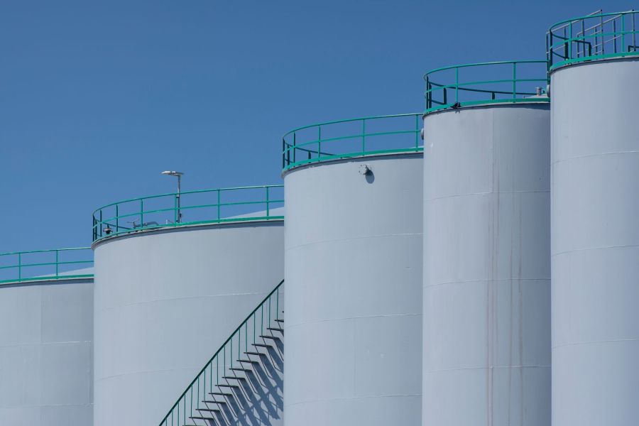 A row of petroleum storage tanks against a clear sky